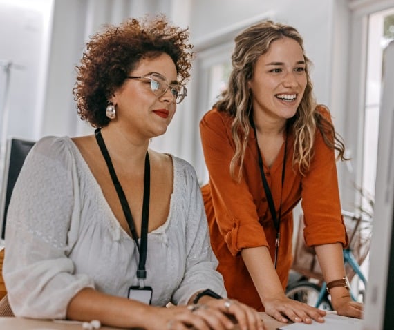 Two women smiling and looking at computer screen