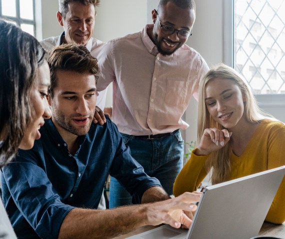 5 coworkers looking at a laptop