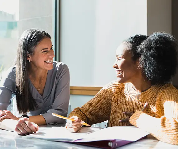 Two women laughing while working on a laptop