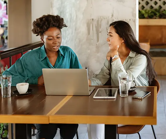 two women talking over a laptop