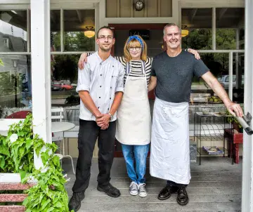 three employees outside restaurant