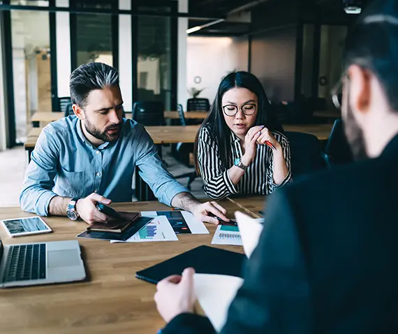 Three people sitting at a table reviewing reports